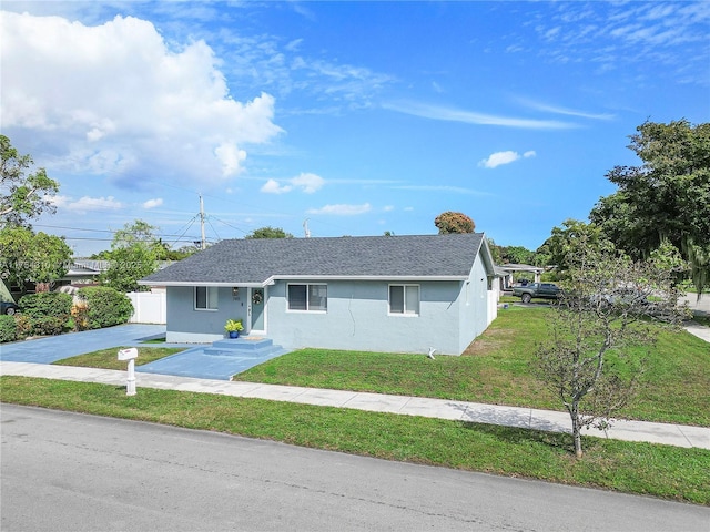 view of front of house featuring a front yard, roof with shingles, and stucco siding