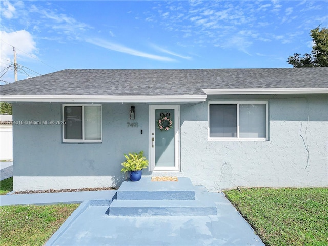 doorway to property featuring stucco siding and roof with shingles