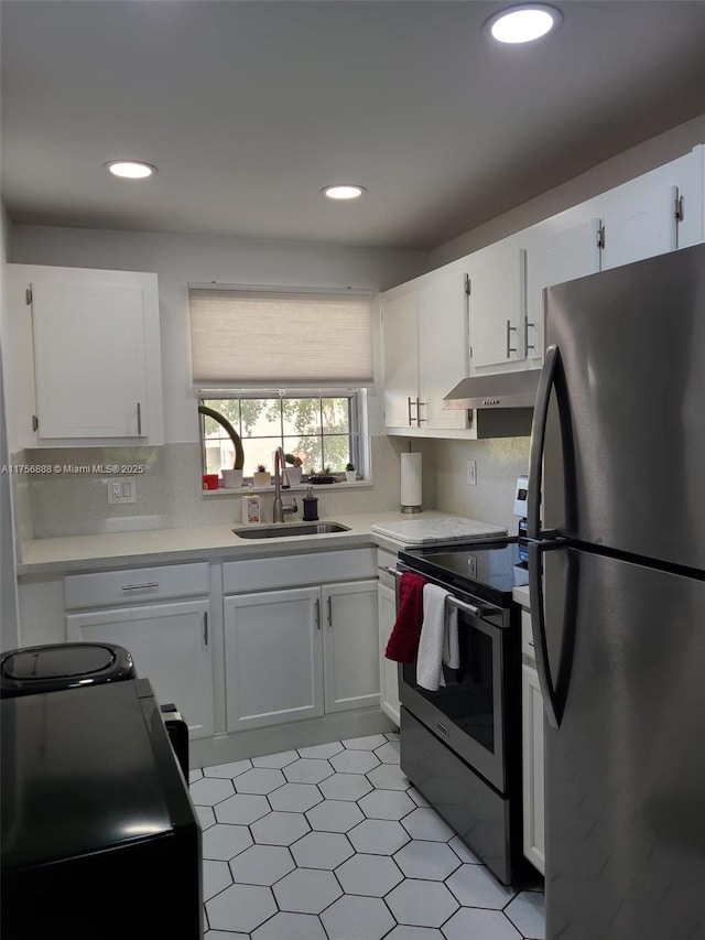 kitchen with stainless steel appliances, light countertops, white cabinets, a sink, and under cabinet range hood