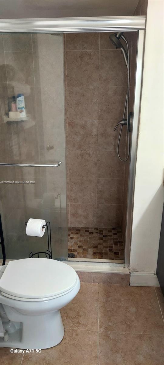 full bathroom with a shower stall, toilet, and tile patterned floors