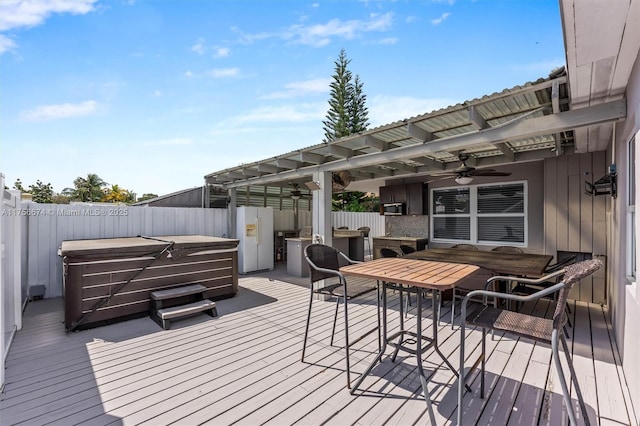 deck featuring ceiling fan, a hot tub, fence, and outdoor dining area