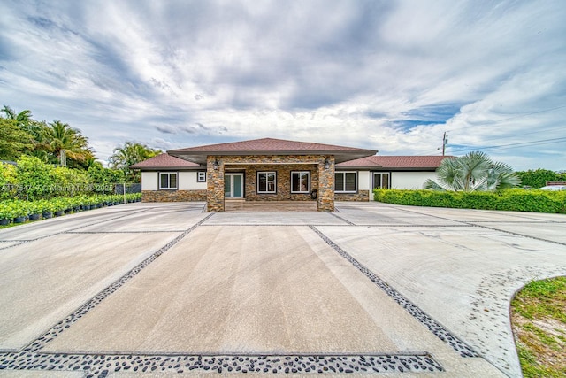 view of front of house featuring stone siding, fence, and stucco siding