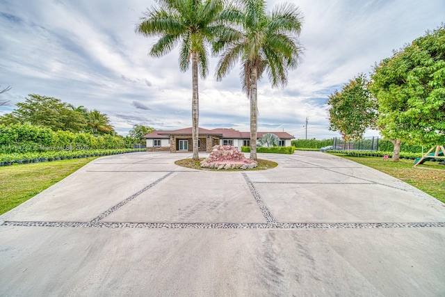 view of front of home with a front yard, curved driveway, a trampoline, and a playground
