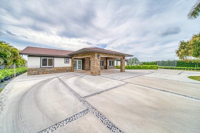 prairie-style home featuring a trampoline, fence, stone siding, and stucco siding