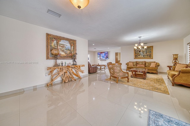 living area featuring a chandelier, a textured ceiling, baseboards, and visible vents