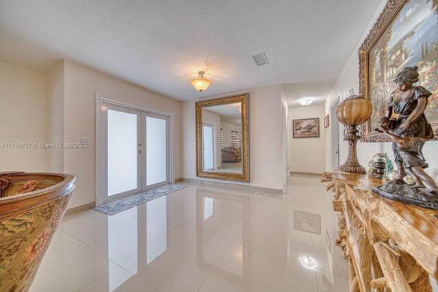 interior space with visible vents, baseboards, light tile patterned floors, a textured ceiling, and french doors