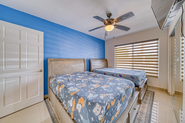 tiled bedroom with a textured wall, a textured ceiling, and baseboards