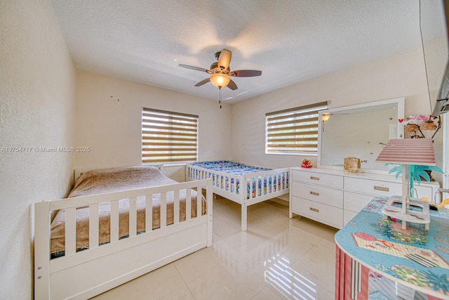 bedroom featuring multiple windows, ceiling fan, a textured ceiling, and light tile patterned floors