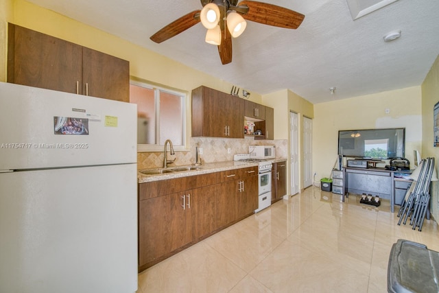 kitchen featuring white appliances, brown cabinetry, a sink, a textured ceiling, and backsplash