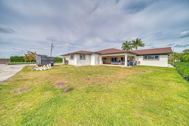 back of property featuring a patio area, a lawn, and stucco siding