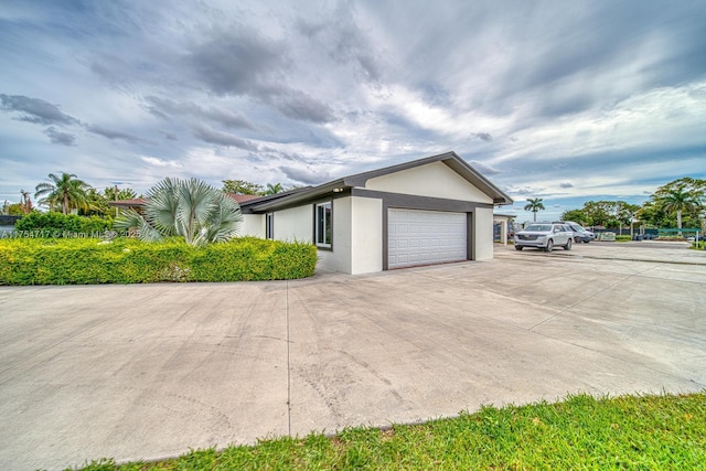 view of side of property with a garage, concrete driveway, and stucco siding