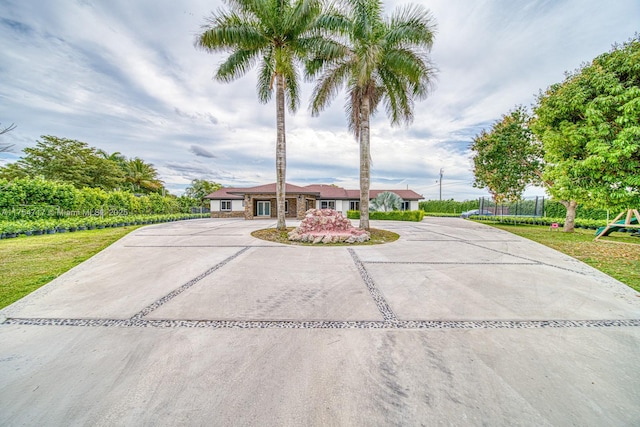 view of front of house featuring driveway, a front lawn, a trampoline, and a playground