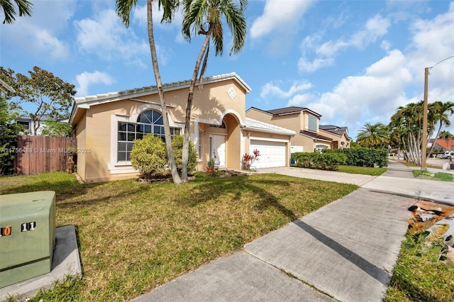 mediterranean / spanish home with a front yard, concrete driveway, fence, and stucco siding