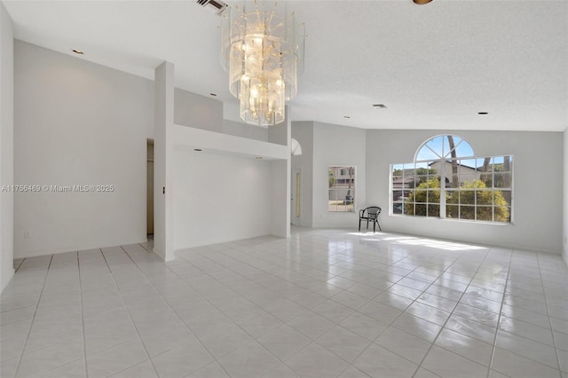 unfurnished room featuring a textured ceiling, high vaulted ceiling, light tile patterned flooring, visible vents, and an inviting chandelier