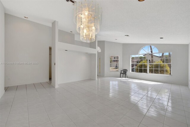9820 SW 154th Pl, Miami, FL 33196 - empty room with visible vents, high vaulted ceiling, light tile patterned floors, a notable chandelier, and a textured ceiling