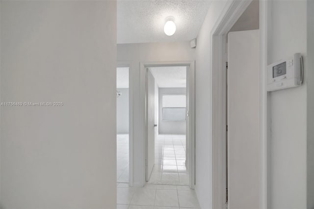 hall featuring a textured ceiling and light tile patterned floors