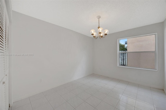 spare room with light tile patterned floors, a textured ceiling, and an inviting chandelier