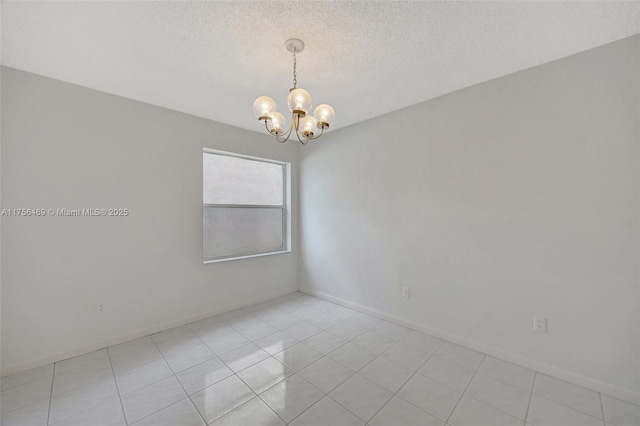 spare room featuring a textured ceiling, a chandelier, and baseboards