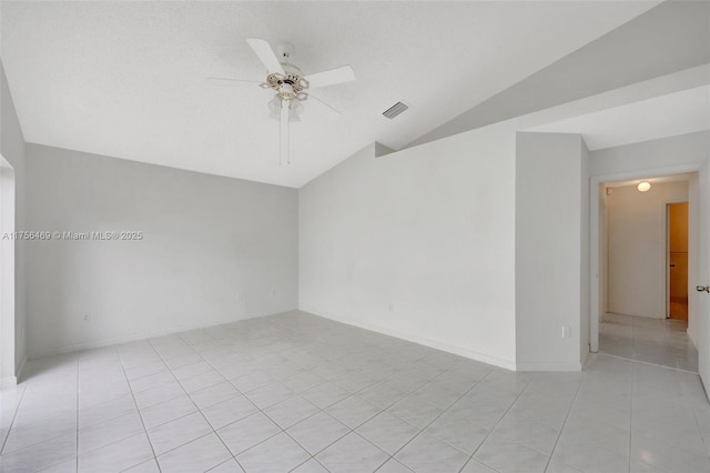 empty room with lofted ceiling, ceiling fan, light tile patterned floors, visible vents, and baseboards