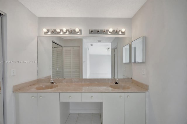 full bath featuring a textured ceiling, tile patterned flooring, and a sink