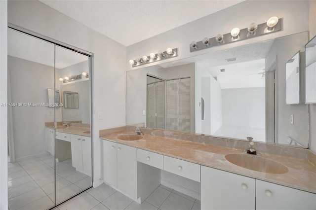 bathroom featuring a textured ceiling, double vanity, tile patterned flooring, and a sink