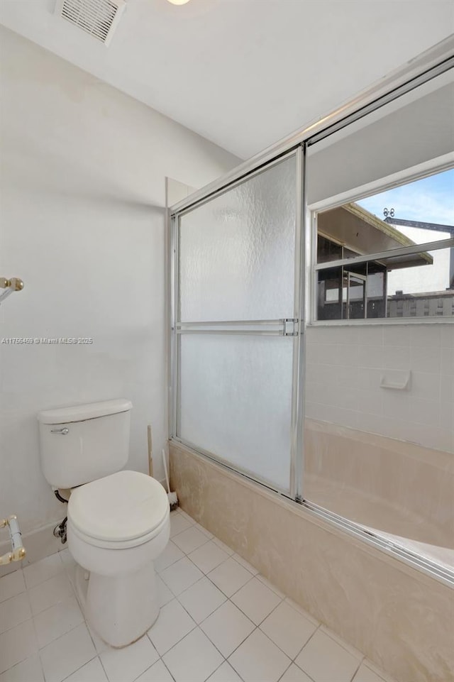 bathroom with toilet, bath / shower combo with glass door, tile patterned flooring, and visible vents