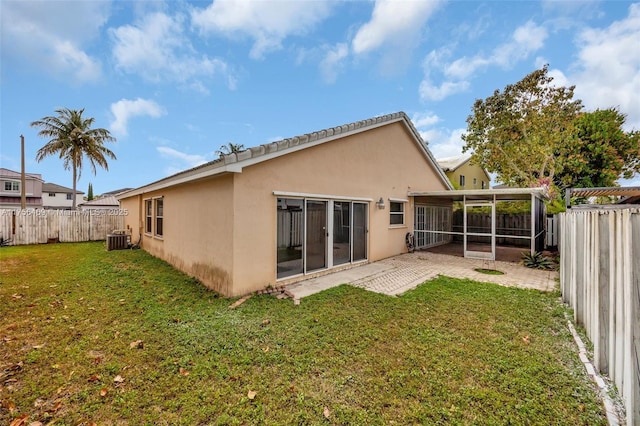 back of property featuring stucco siding, a lawn, central AC unit, a sunroom, and a fenced backyard