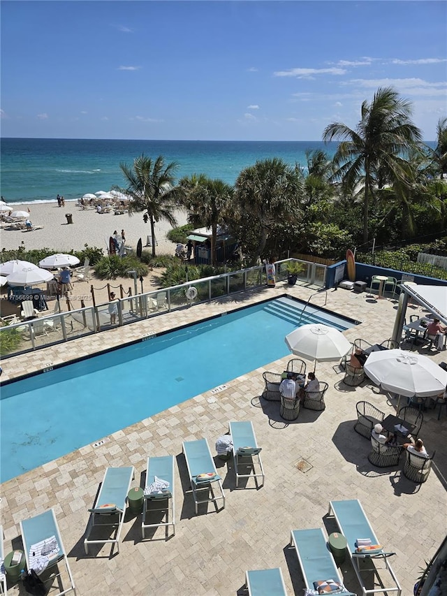 community pool featuring a patio area, a water view, and fence