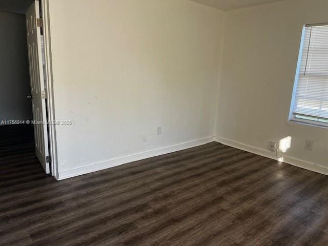 spare room with dark wood-type flooring and baseboards