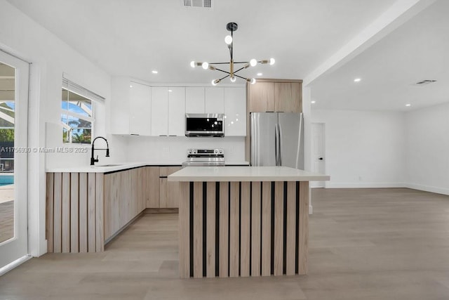 kitchen with stainless steel appliances, a sink, light wood-style flooring, and modern cabinets