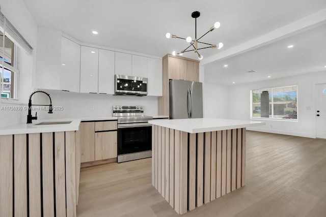 kitchen featuring light wood finished floors, appliances with stainless steel finishes, modern cabinets, and a sink