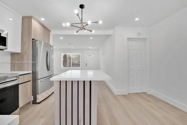 kitchen featuring light wood finished floors, stainless steel appliances, light countertops, light brown cabinetry, and modern cabinets