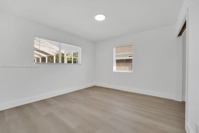 spare room with baseboards and wood finished floors