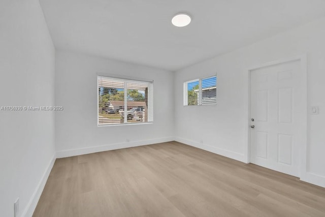 spare room with baseboards and light wood finished floors