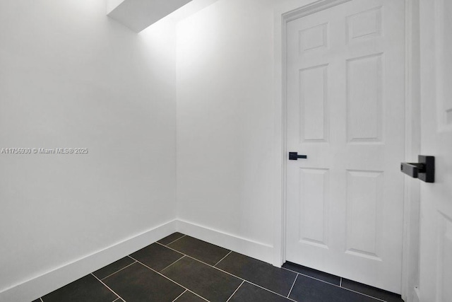 interior space with dark tile patterned flooring and baseboards