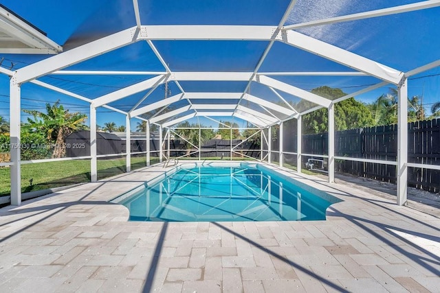 view of pool with a storage shed, glass enclosure, a patio area, a fenced backyard, and an outdoor structure