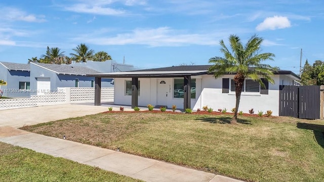 ranch-style house featuring covered porch, fence, concrete driveway, stucco siding, and a front yard