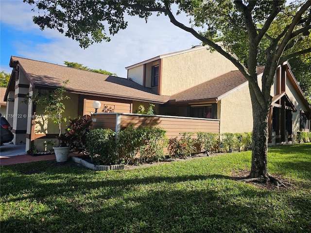 view of home's exterior with a shingled roof, a lawn, and stucco siding