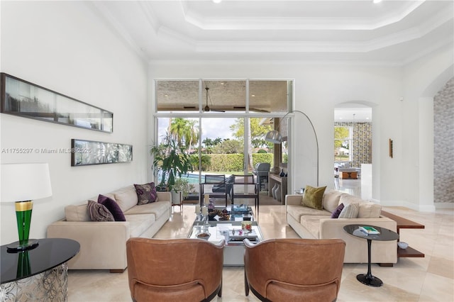 living area with arched walkways, crown molding, a raised ceiling, a high ceiling, and light tile patterned flooring