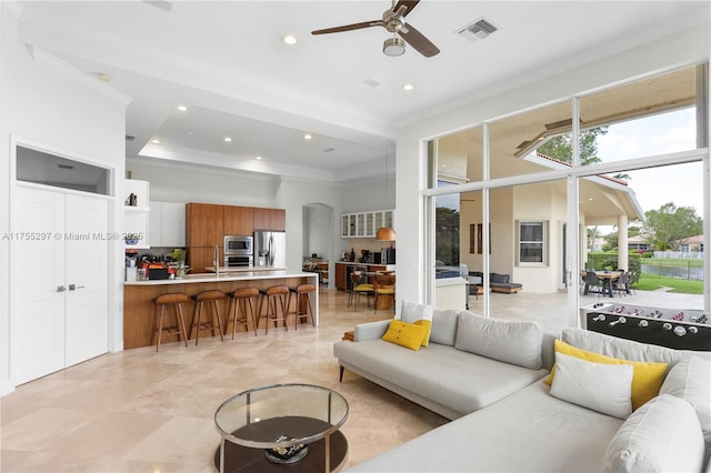 living area featuring arched walkways, recessed lighting, visible vents, a towering ceiling, and ornamental molding