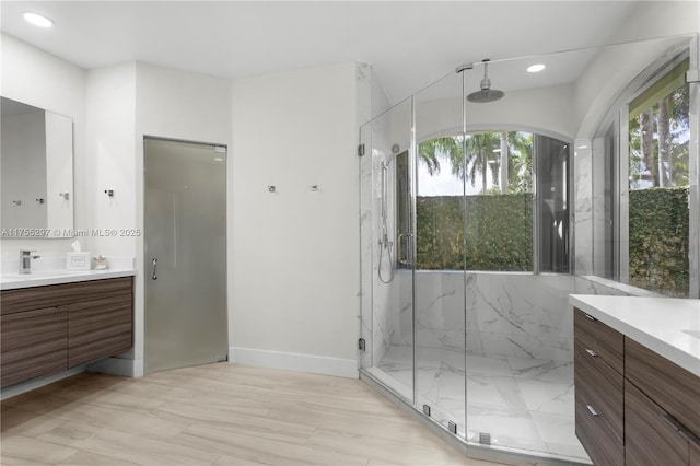 bathroom featuring recessed lighting, a marble finish shower, and vanity