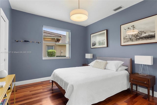 bedroom featuring visible vents, baseboards, and wood finished floors