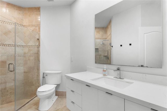 full bathroom featuring toilet, vanity, a shower stall, baseboards, and tile patterned floors