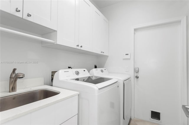 laundry area with cabinet space, washing machine and dryer, and a sink