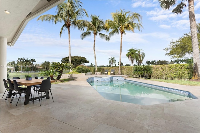 view of swimming pool featuring outdoor dining space, a pool with connected hot tub, a patio area, and fence