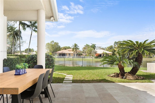 view of patio with outdoor dining area, a water view, and fence