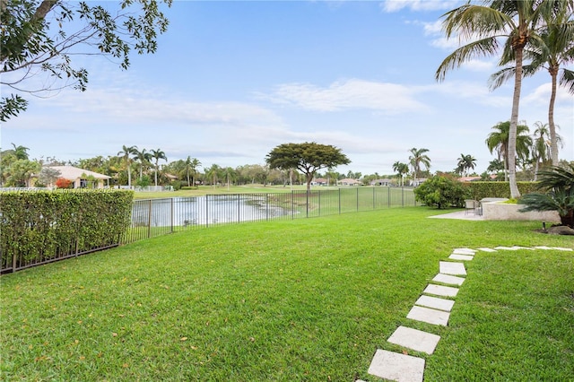 view of yard with a water view, a fenced backyard, and a patio