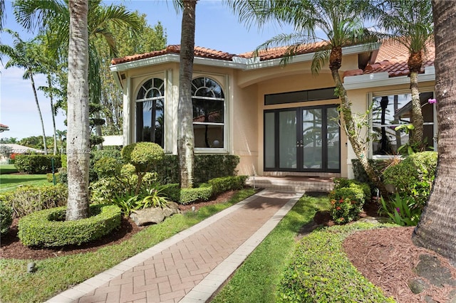 doorway to property featuring french doors, a tiled roof, and stucco siding