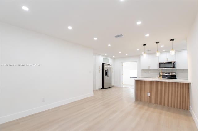 kitchen with stainless steel appliances, recessed lighting, light countertops, visible vents, and light wood-type flooring