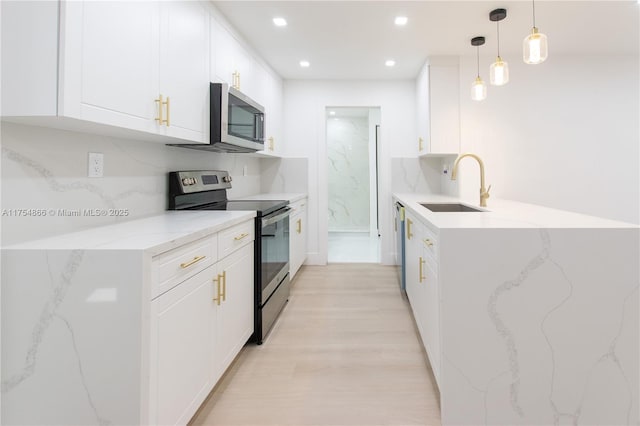 kitchen featuring a peninsula, a sink, white cabinets, appliances with stainless steel finishes, and backsplash